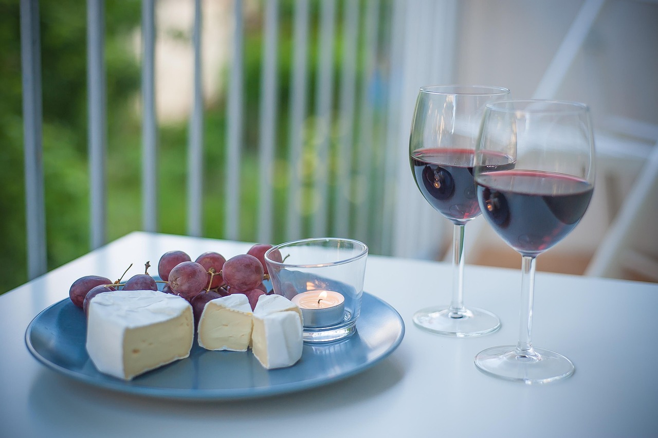 Käse, Trauben und Rotwein auf einem rustikalen Tisch