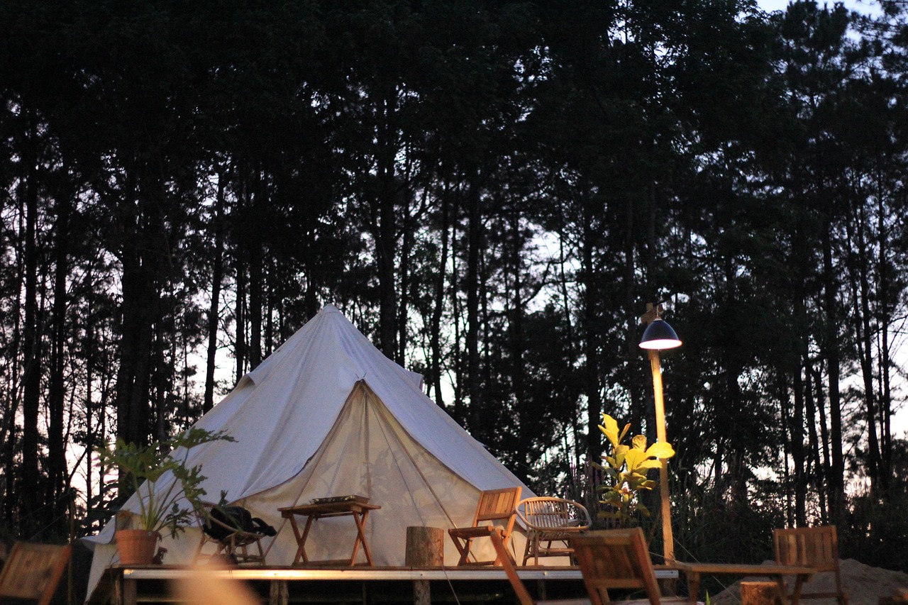 Beleuchtetes Lodge-Zelt mit Holzterrasse im Pinienwald