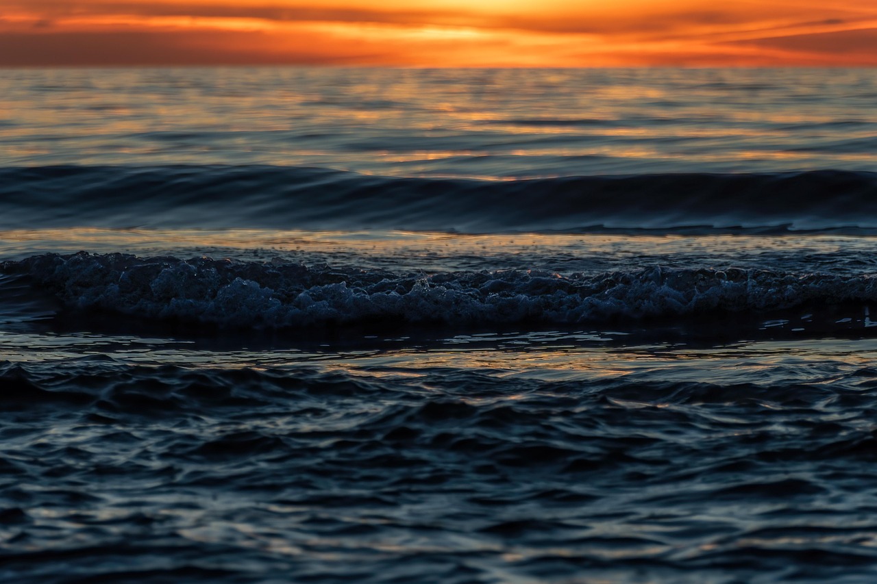 Wellen laufen bei Dämmerung auf einen einsamen Strand