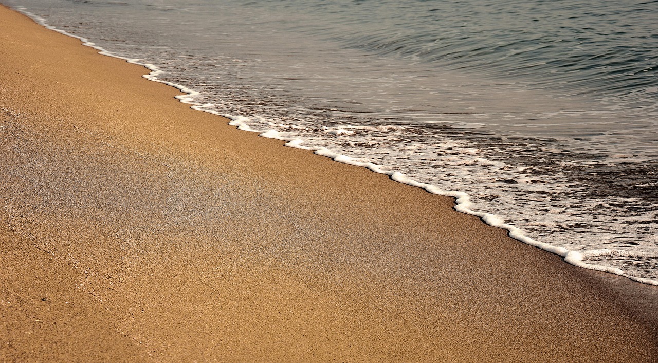 Wellen laufen sanft auf hellen Sandstrand